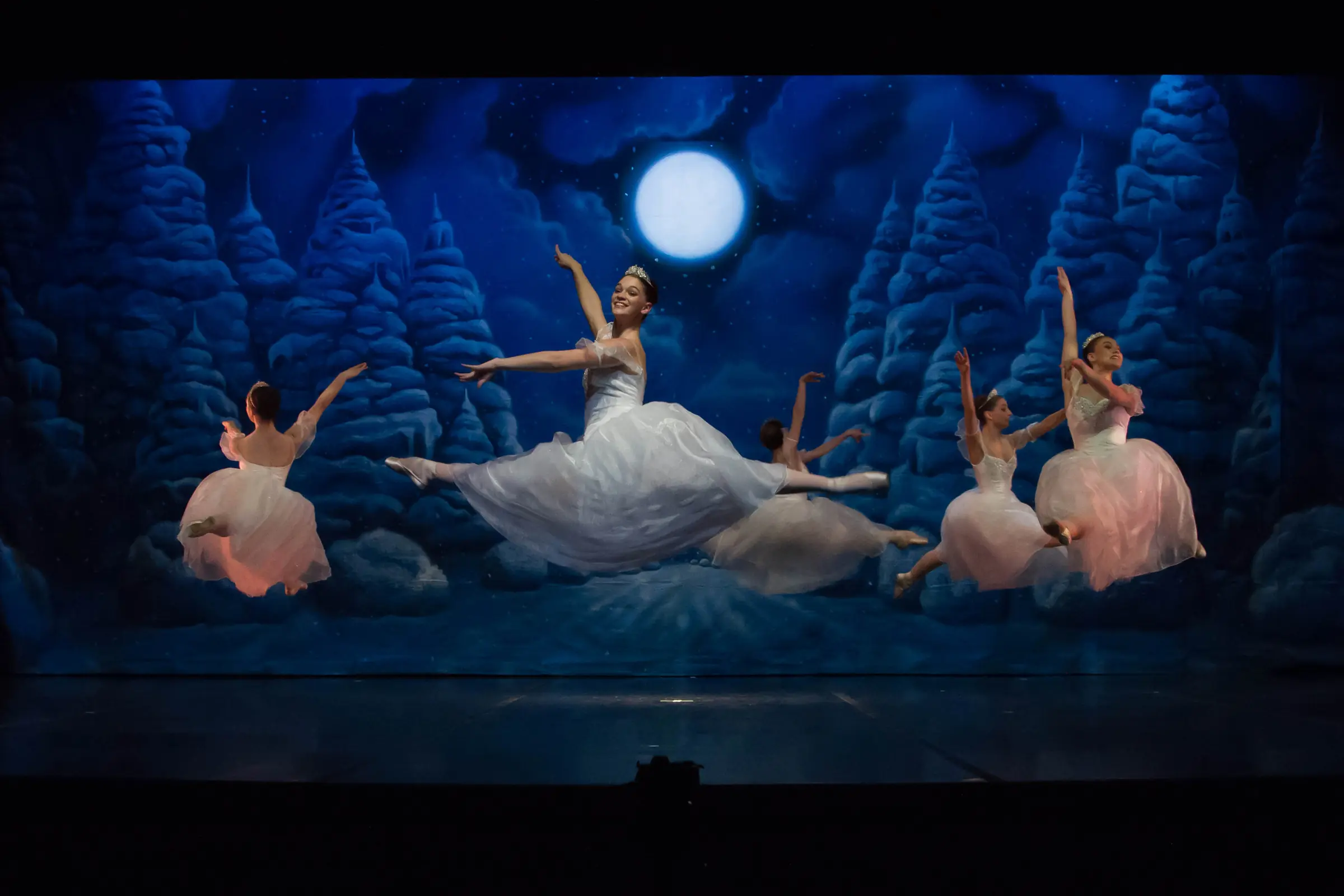 The Snow Queen leaps across a moonlit forest with the snowflake corps in Ballet for Youth’s Nutcracker