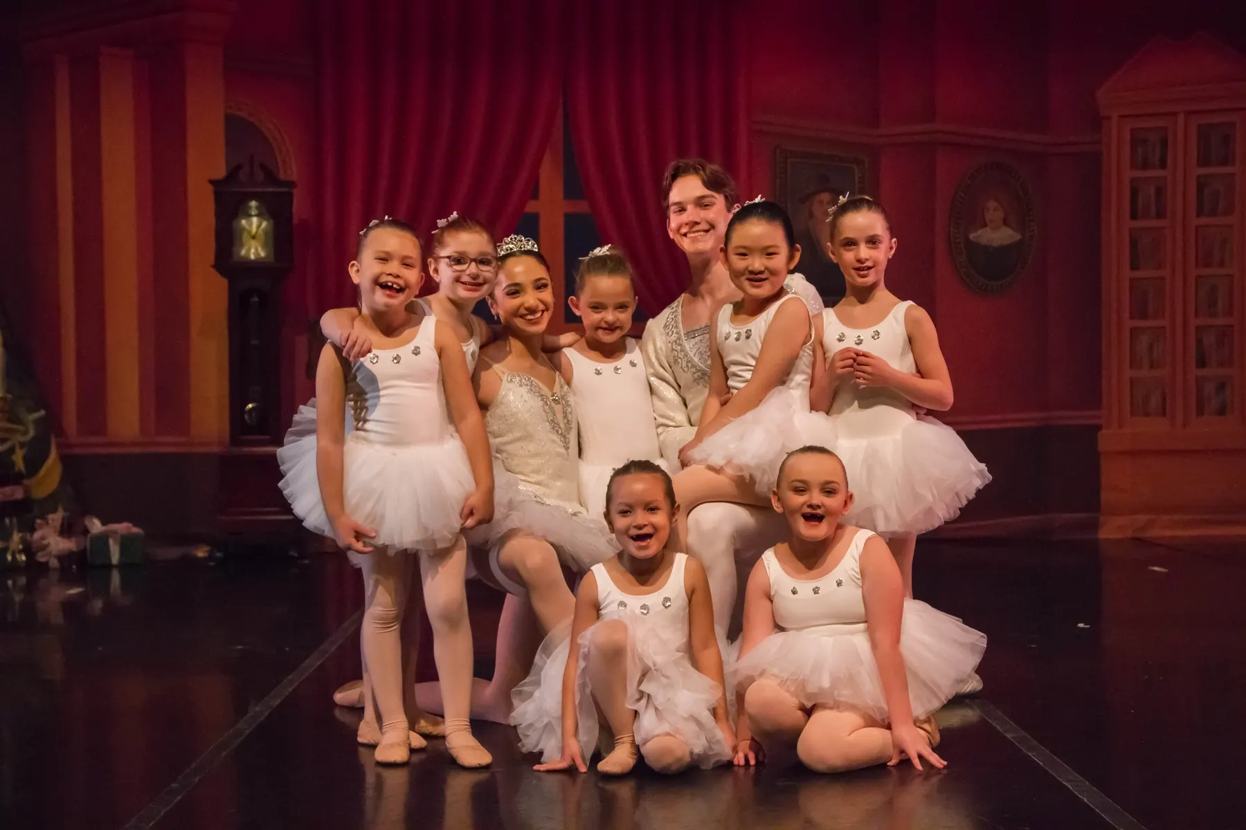 Young Ballet for Youth dancers in white tutus smiling on stage with an older dancer